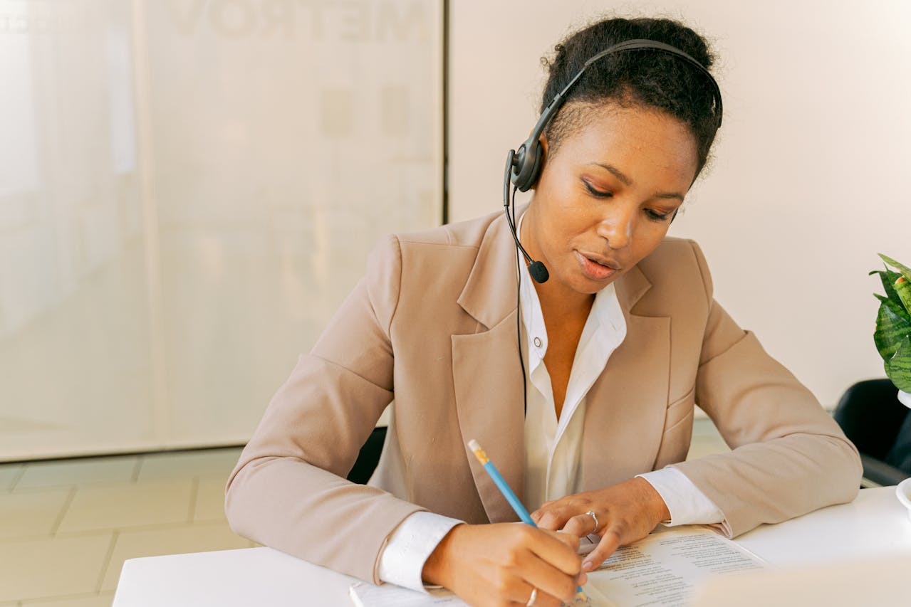 A woman wearing a headset writing notes